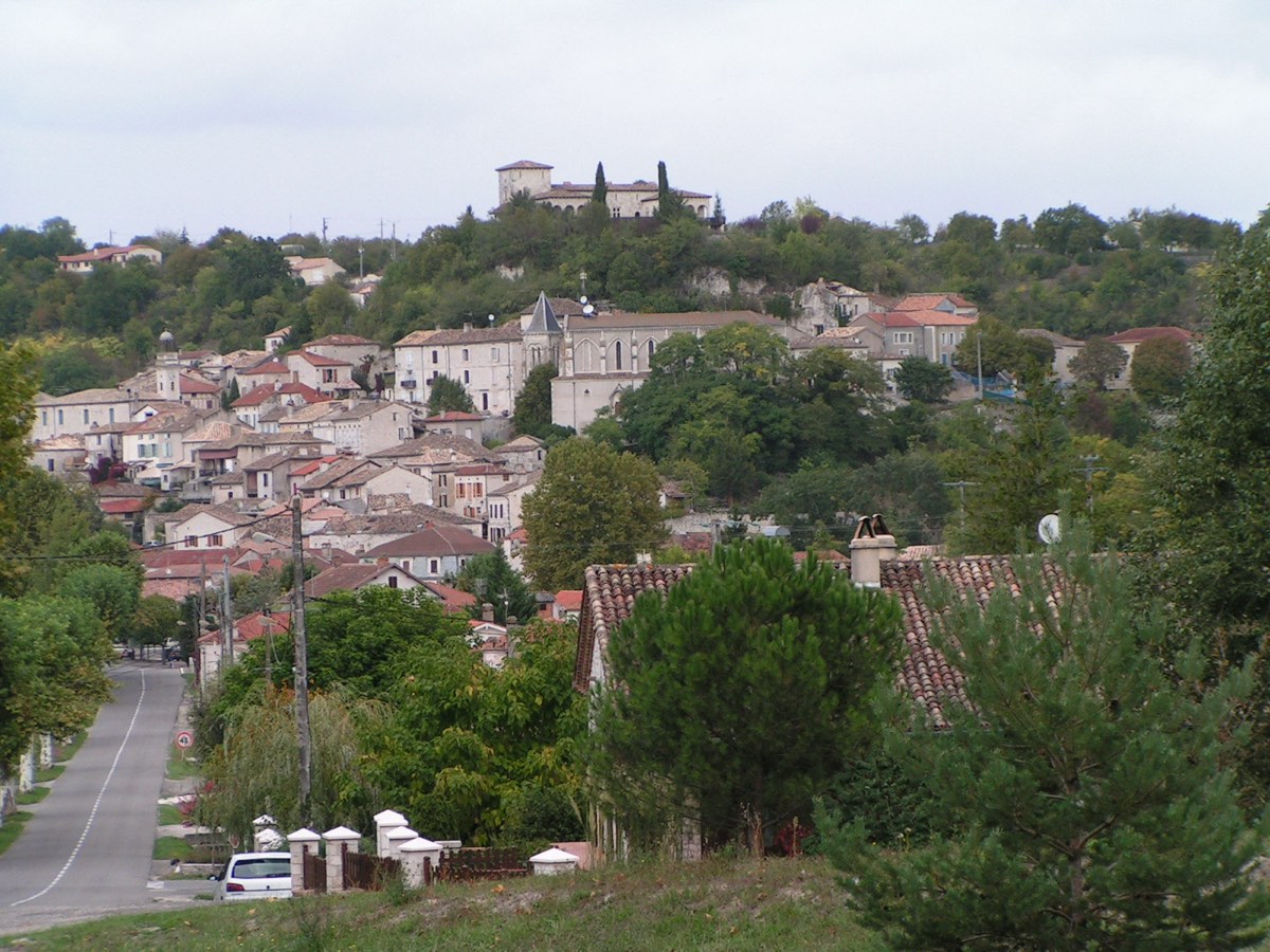 Le village de Montaigu-de-Quercy sur sa colline, maisons en pierre et château au sommet.